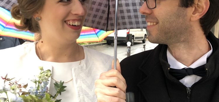 bride and groom under umbrella rainy day wedding