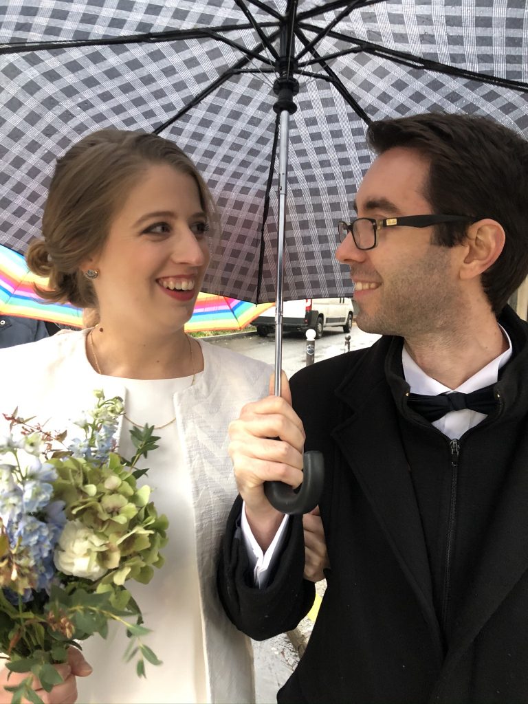 bride and groom under umbrella rainy day wedding