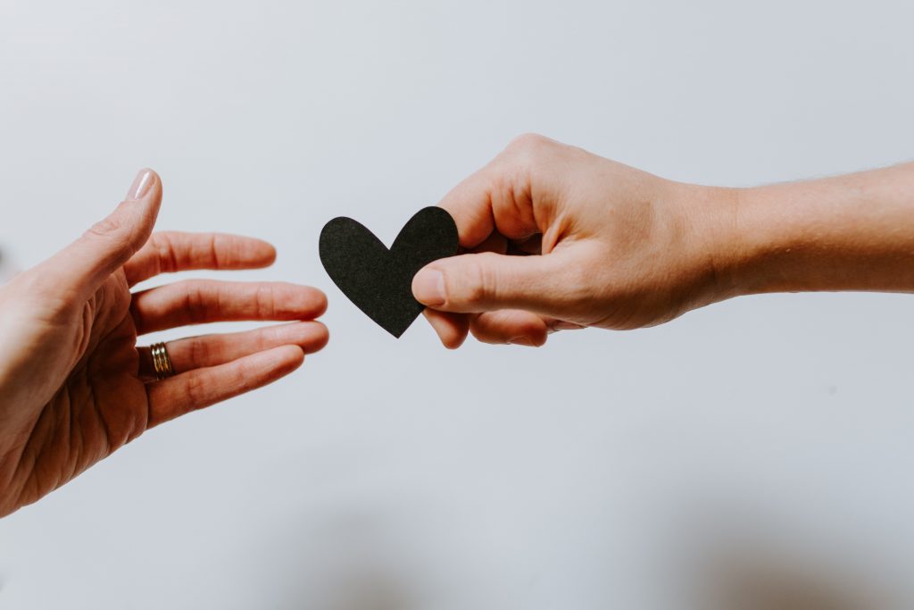 handing over a cut out black paper heart