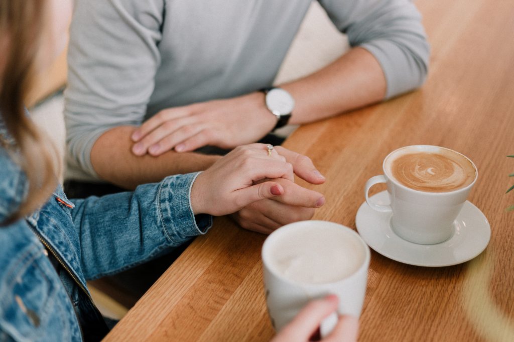 a couple holding hands in a café drinking coffee