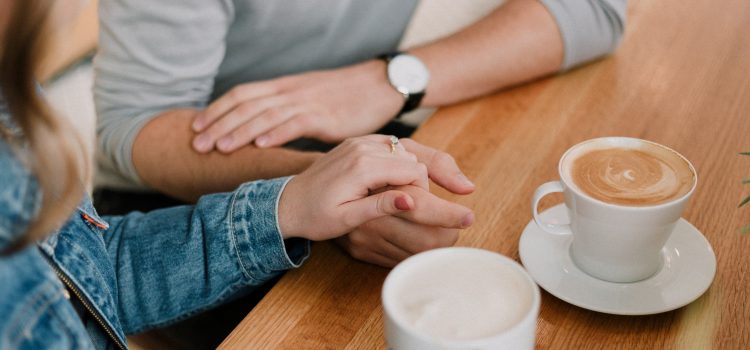 a couple holding hands in a café drinking coffee