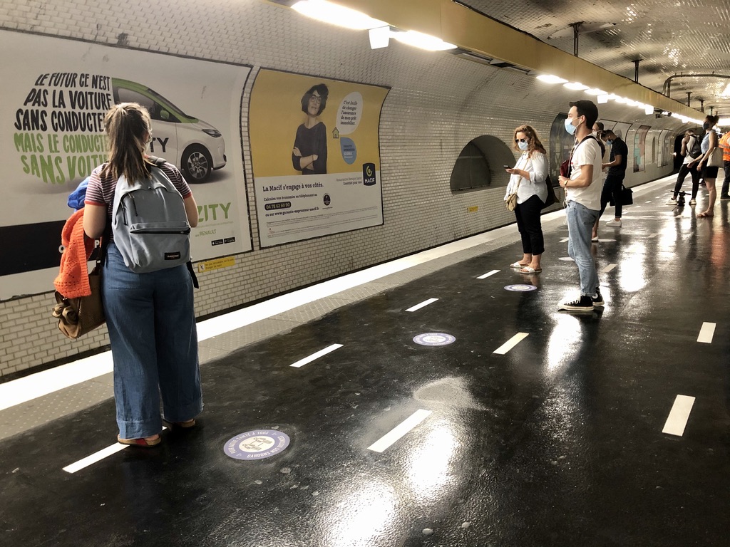 white markings on the ground of the metro stop to encourage spacing between people