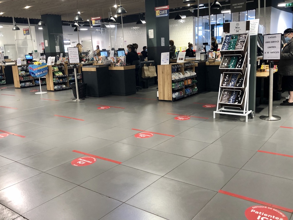 red lines on the ground for spacing and plastic sheets in hanging in front of cashiers at the grocery store