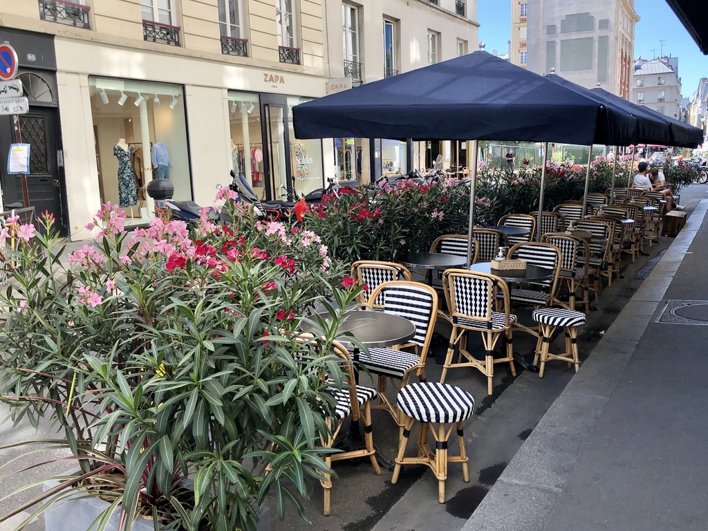 outdoor restaurant seating in Paris with colorful flowers and blue umbrellas