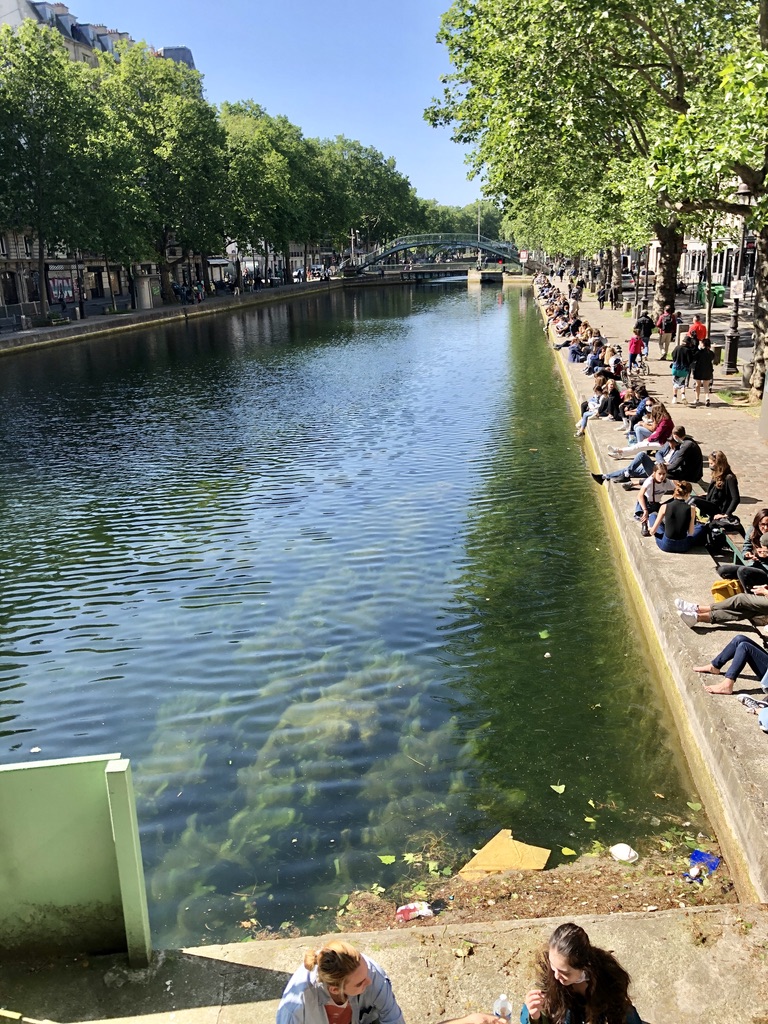 young people lined up, sitting all along Canal Saint Martin on a sunny day