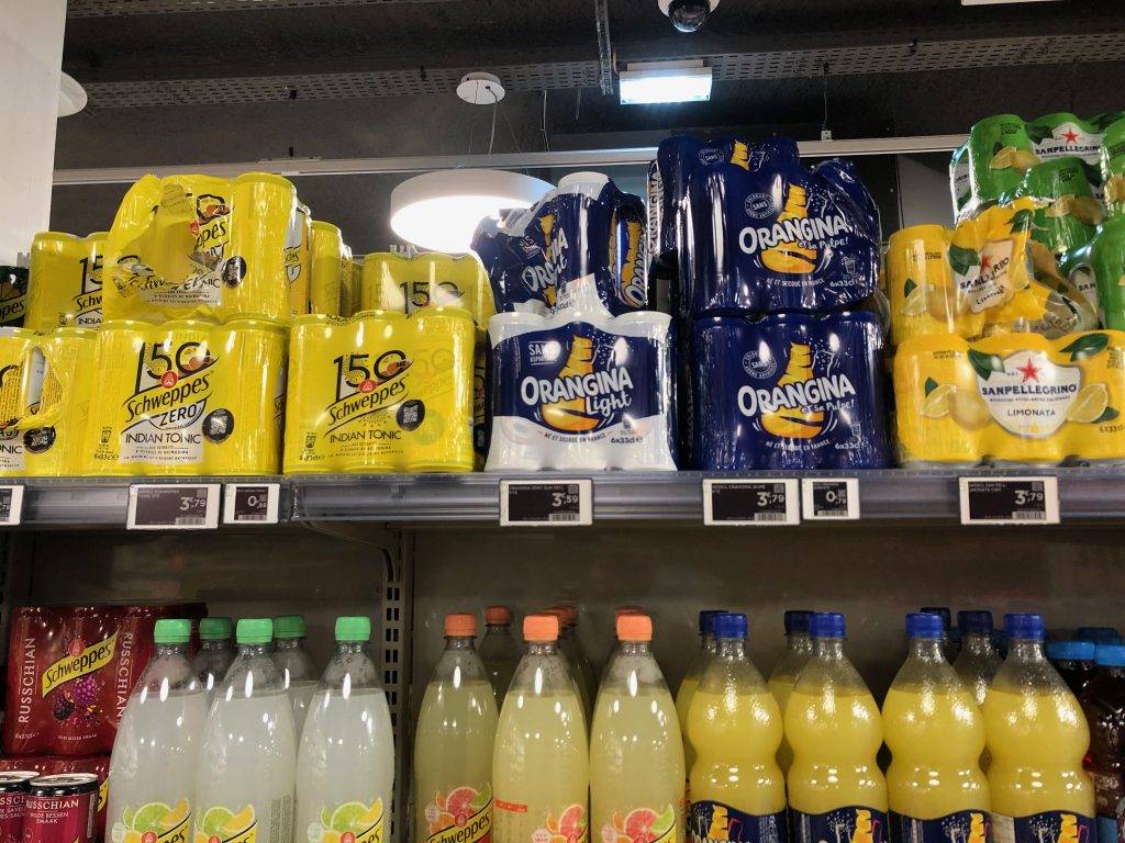 schweppes, orangina, and san pelligrino cans in grocery store in Paris, France