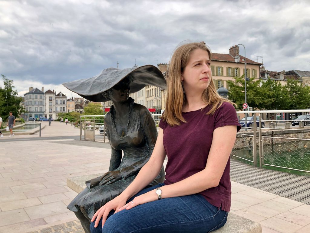woman sitting next to statue of Lili ou la dame au chapeau in Troyes, France