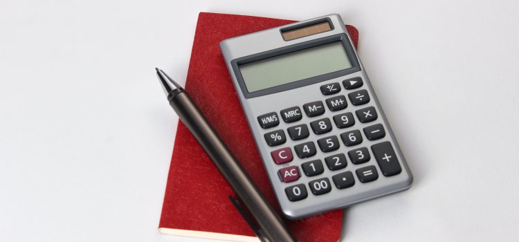 calculator and pen on top of a small notebook