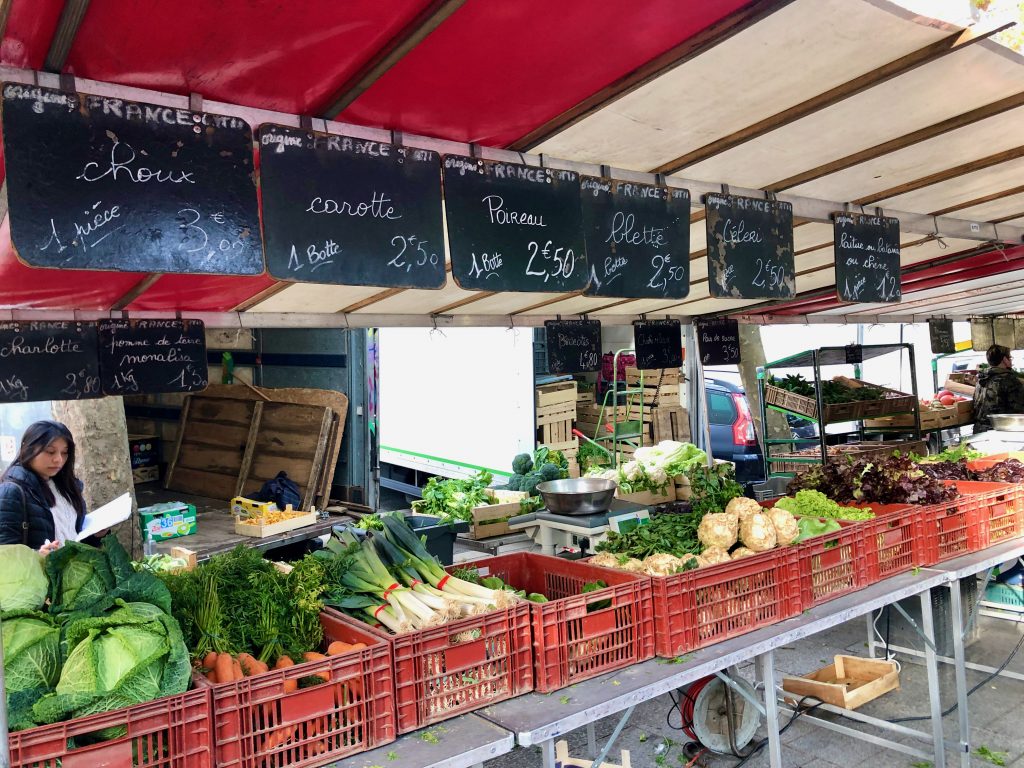 French farmer's market stand with signage indicating produce origin