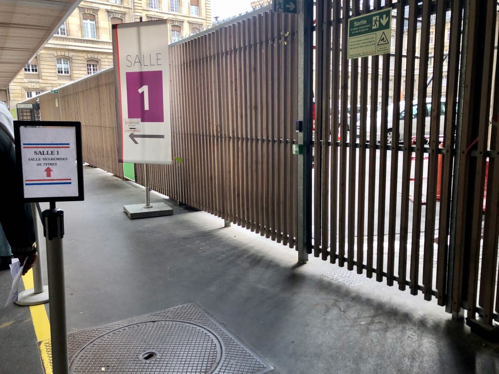 signs indicating the line for Salle 1—Salle des Remises at the Paris préfecture and where to wait to pick up your carte de séjour