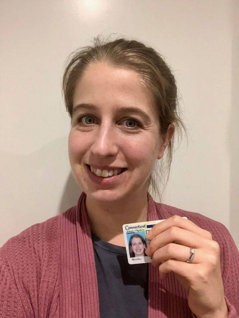 woman smiling and holding a Connecticut driver's license