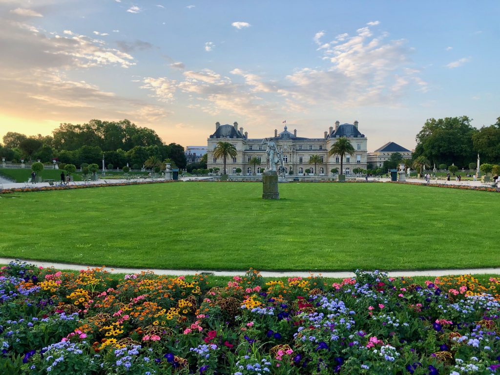 looking across Jardin du Luxembourg mid-Summer, the grass is vibrant green and there are colorful flowers
