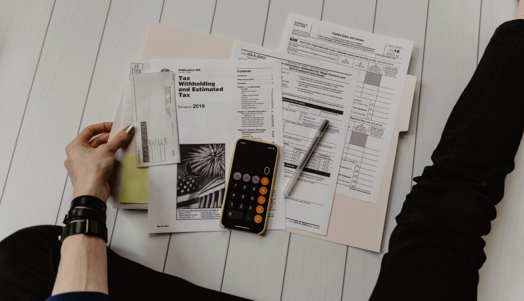 aerial view of US tax paperwork in a folder on the floor with a calculator