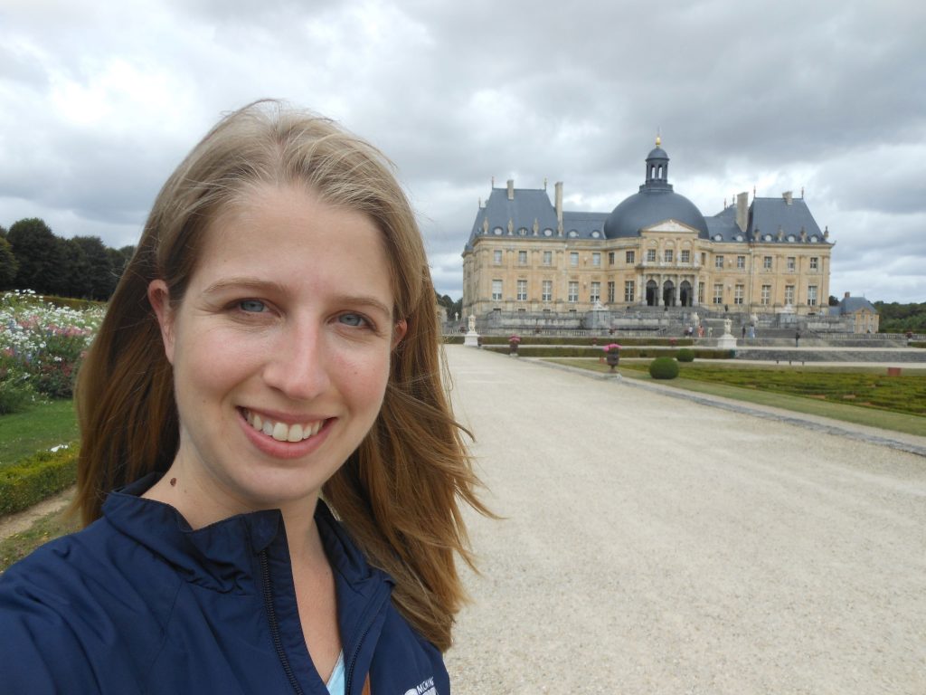woman with Château de Vaux-le-Vicomte in the background on a cloudy day