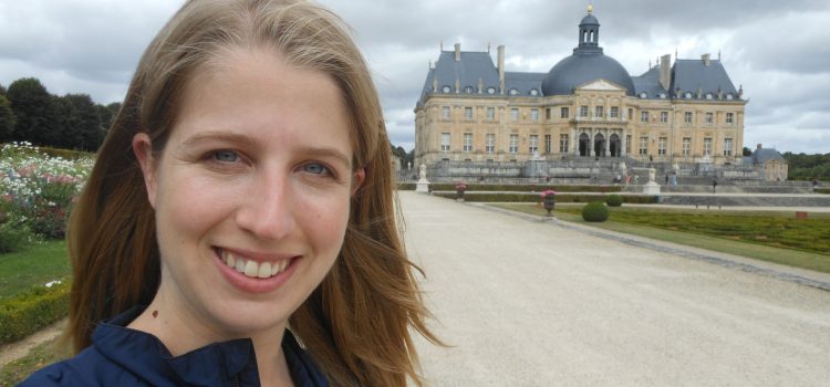 woman with Château de Vaux-le-Vicomte in the background on a cloudy day