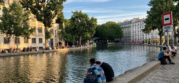 Why You (Still) Can’t Speak French and What to Do About It People sitting along Canal Saint-Martin at golden hour