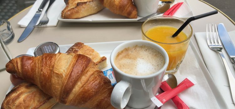 a typical breakfast in France ordered as a formule from a French café in Paris: croissant, baguette (tartine), cup of coffee, glass of orange juice, butter, and jam