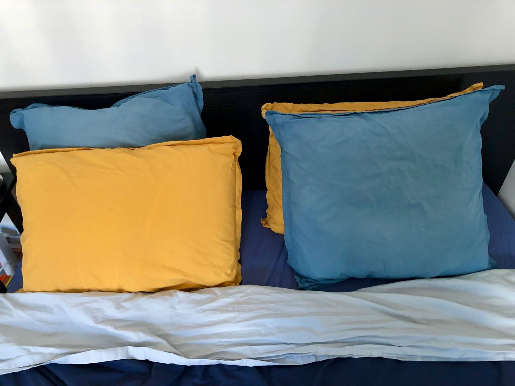 yellow rectangular pillow next to a blue square pillow, typical for sleeping in France