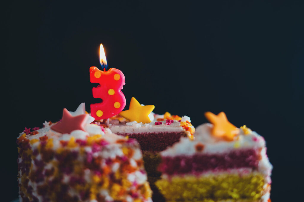 number 3 candle lit on top of a birthday cake