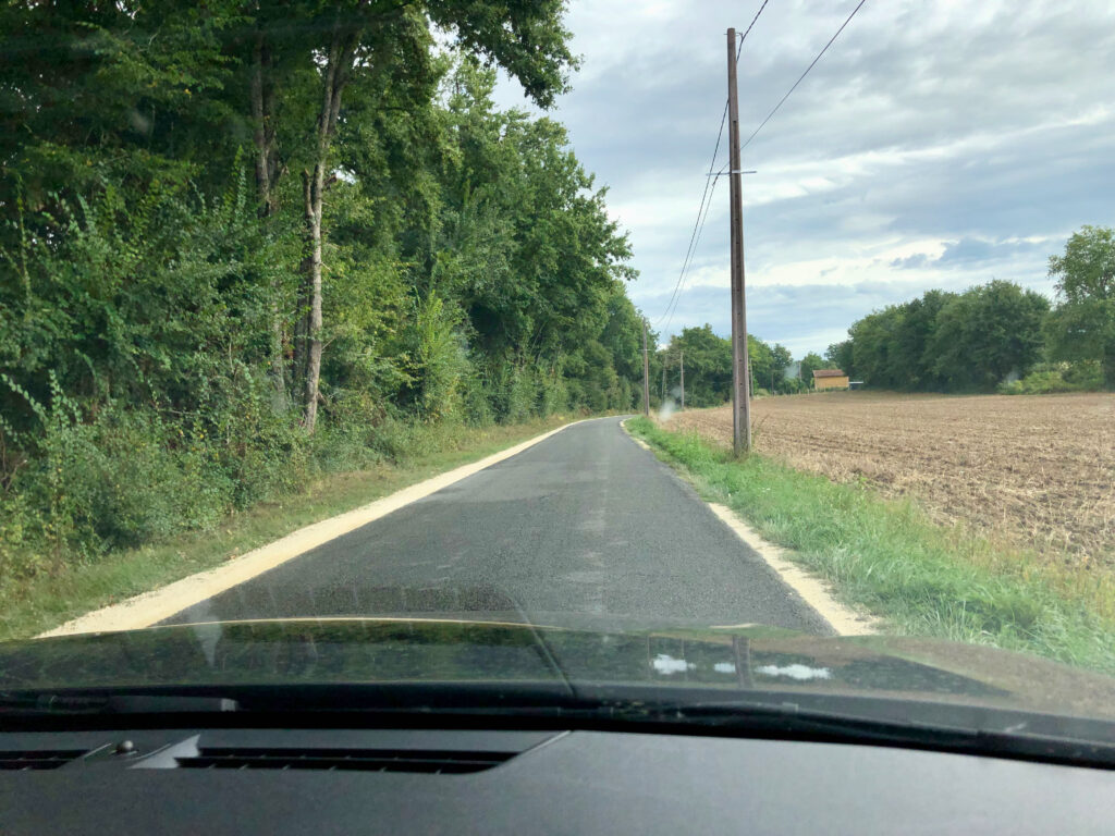 small and narrow rural road in France with sand on either side of the road