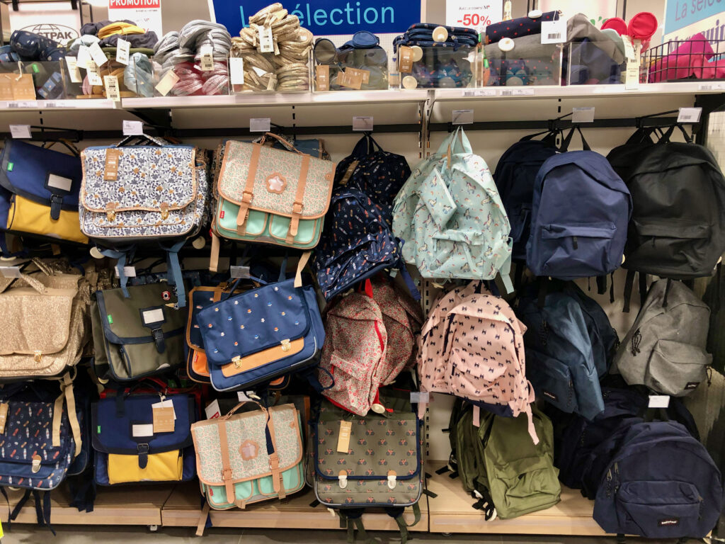 backpacks (sac à dos and cartables) on display in French school supply store