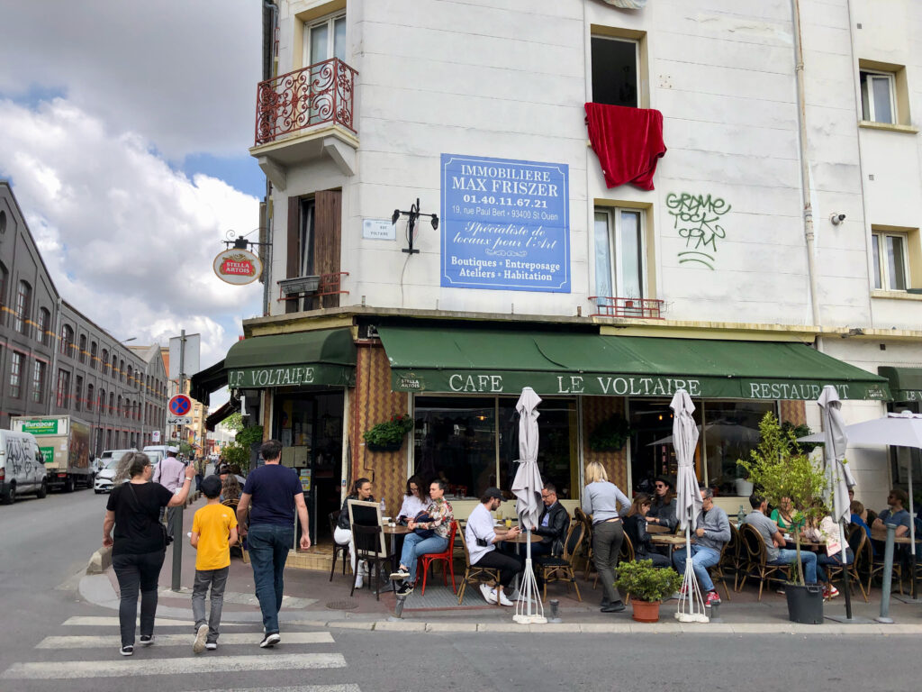 people sitting out and talking on the terrasse in front of a café in Saint-Ouen