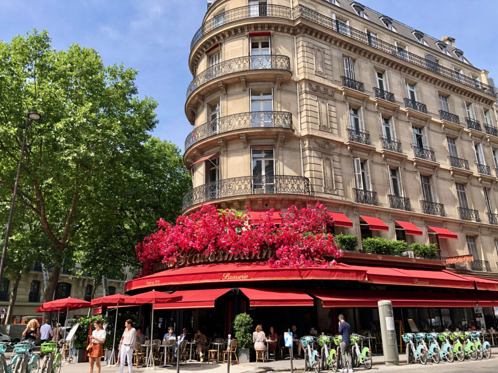 bright red flower decorations over the red awning of a Parisian café in the 9th arrondissement