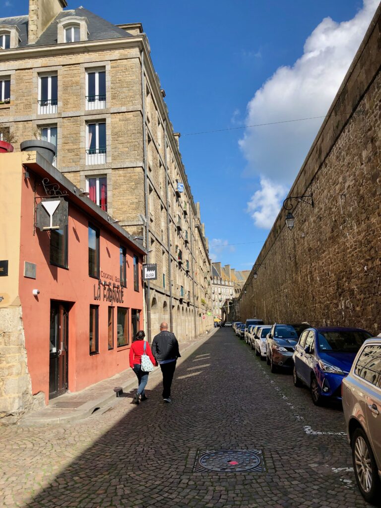 walking down Rue de Chartres in Saint-Malo, with the high stone ramparts on the right side of the street