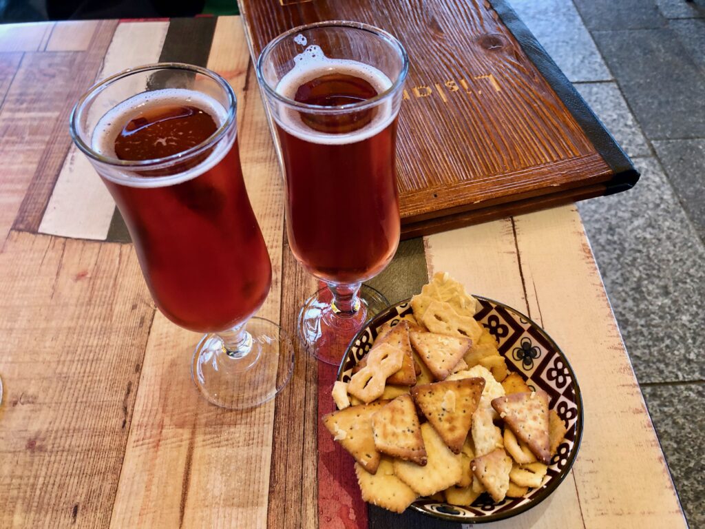 two tall glasses of kir breton next to a bowl of salty snacks for a pre-dinner apéritif in Brittany, France