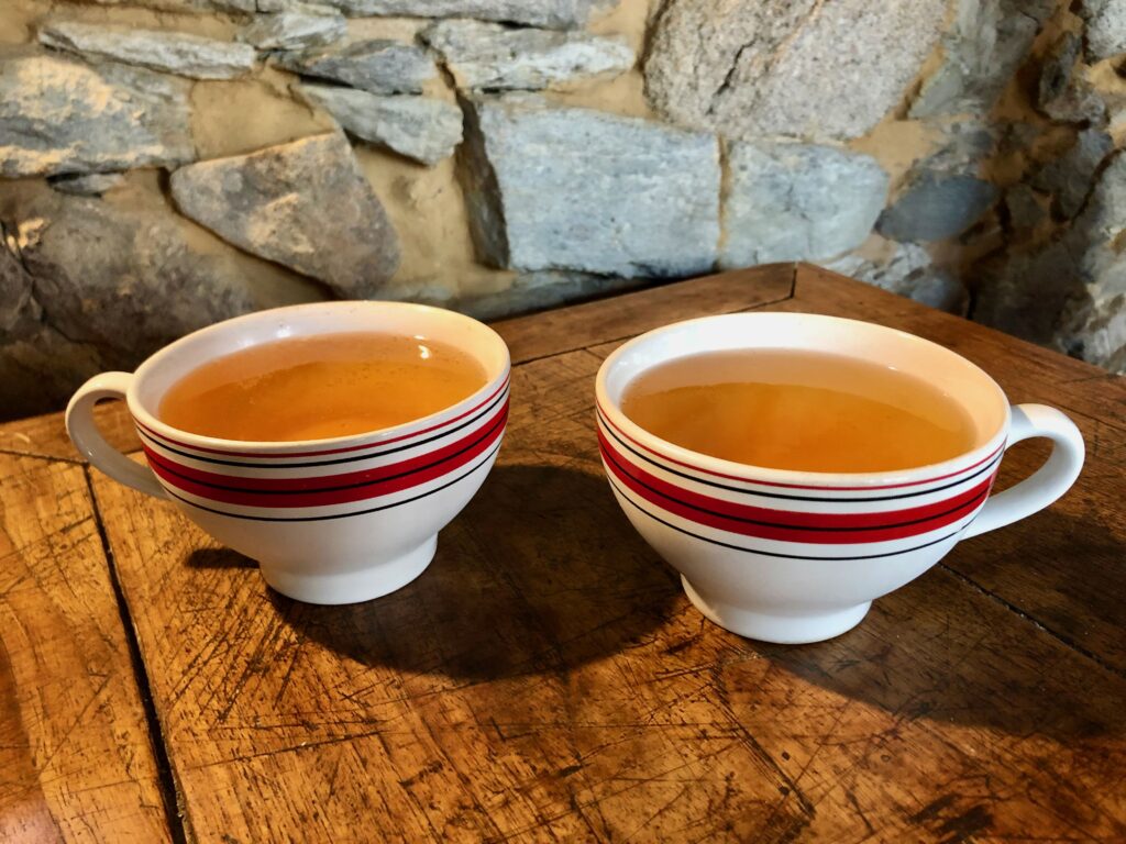 two large mugs of bubbly cider on a wooden table in a traditional breton crêperie
