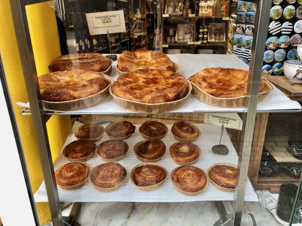 two shelves of kouign-amann, a buttery sugary pastry, in a French bakery storefront window