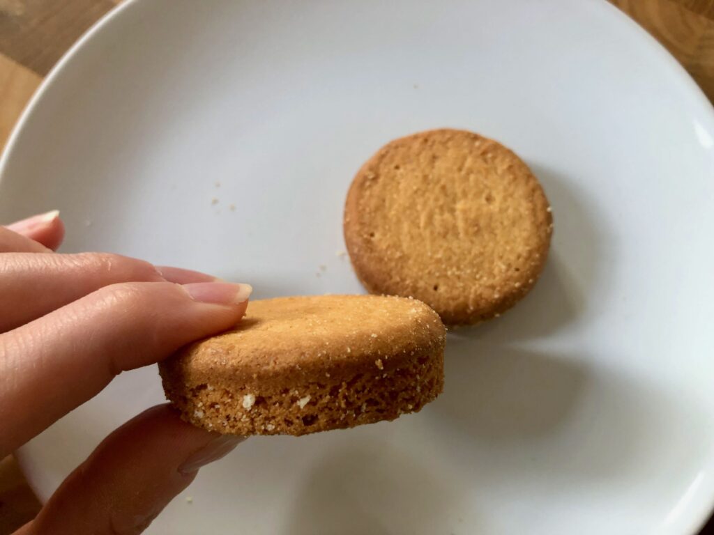 one palet breton (butter cookie from Brittany, France) on a white plate and one palet breton held in hand