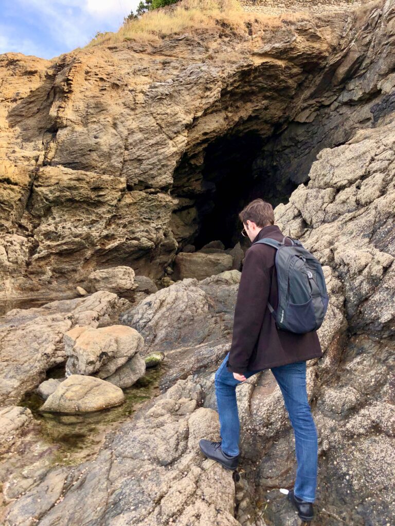 man with Osprey daylite backpack walking towards the Grotte des fées in Dinard, France