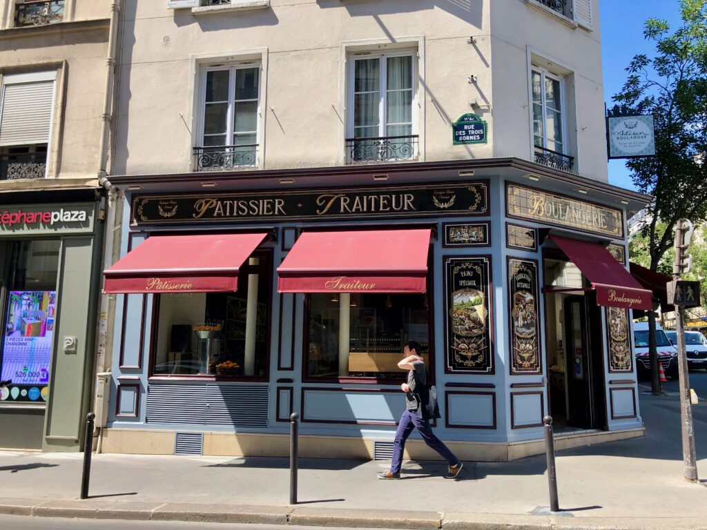 classic Parisian bakery with red awnings and a blue and tiled facade: patissier, traiteur, boulangerie written