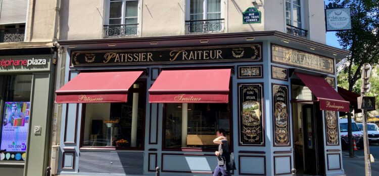 classic Parisian bakery with red awnings and a blue and tiled facade: patissier, traiteur, boulangerie written