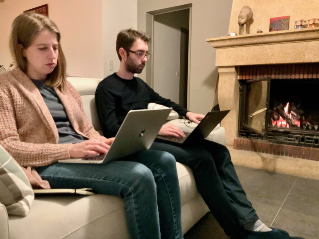 two entrepreneurs, a blogger and a CTO, working on laptops on a couch during the holidays