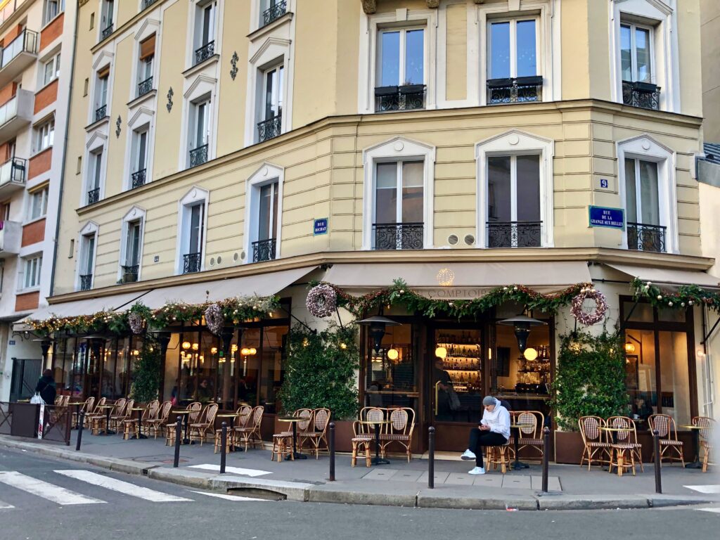 The empty terrasse of a Paris café in the winter with only one person sitting outside