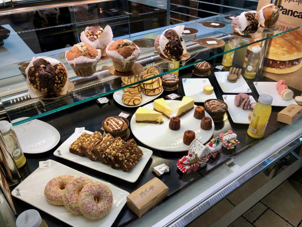 the bakery section of a McDonald's in Paris, France filled with muffins, donuts, cheesecake, brownies, and macarons