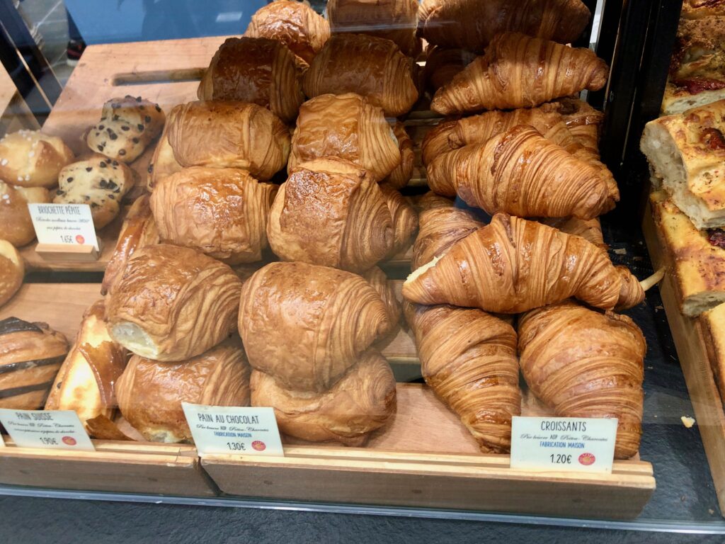 piles of croissants and pains au chocolat on display in a Paris bakery