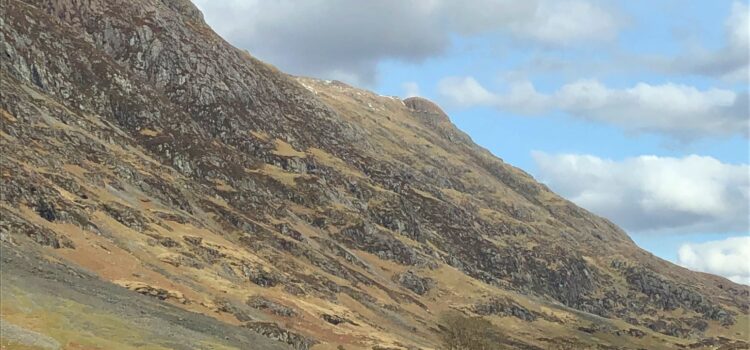 photo taken from the car on the left side of the road in Glencoe Scotland, light blue skies with fluffy clouds