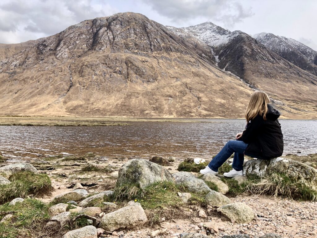 woman sitting on a rock overlooking Glen Etive in Scotland