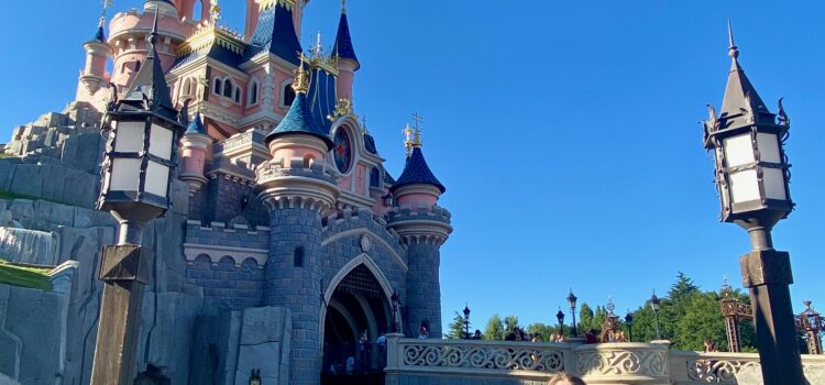 woman standing in front of the Sleeping Beauty Castle in Disneyland Paris on a bright, summer day