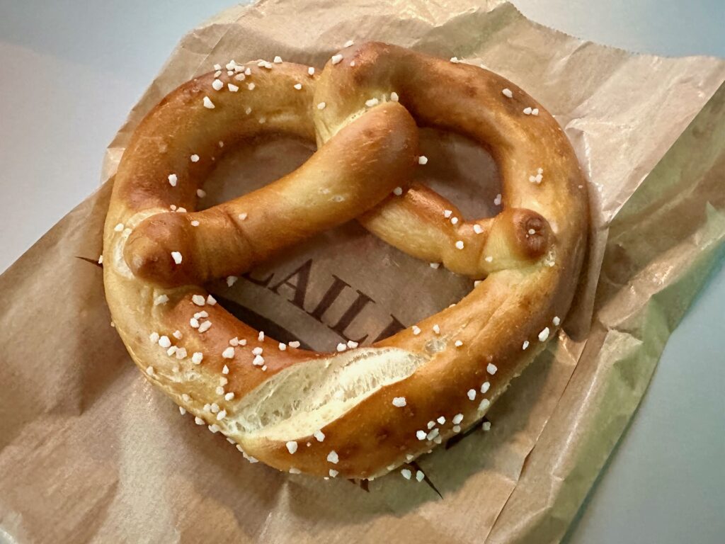 Bretzel, an Alsatian soft pretzel with coarse salt, sits on a paper bag
