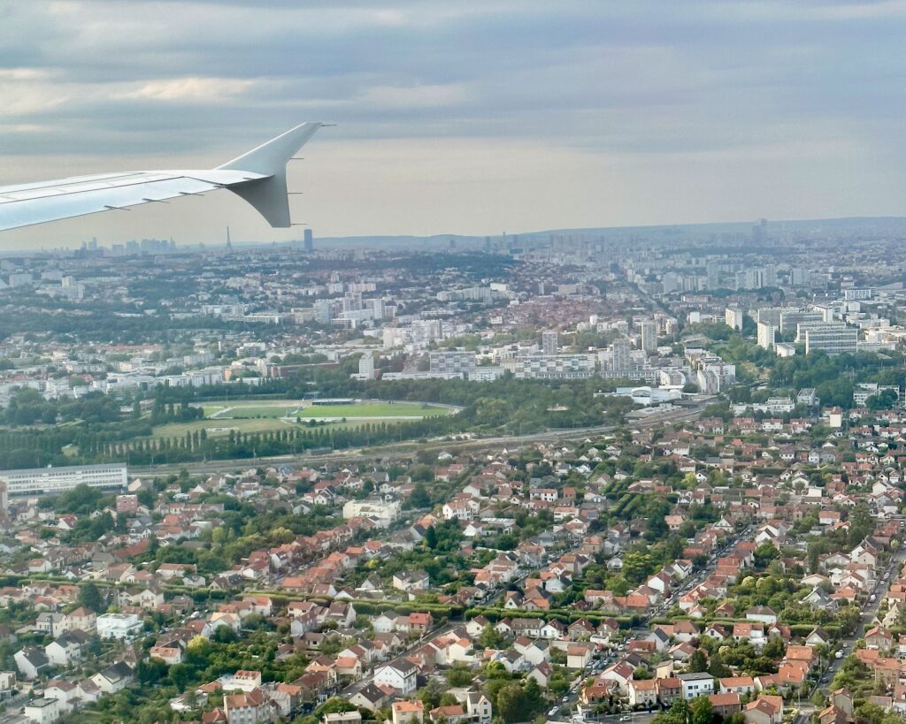 The view out the window of an airplane landing at Orly airport outside of Paris. The Eiffel Tower can be seen in the distance.