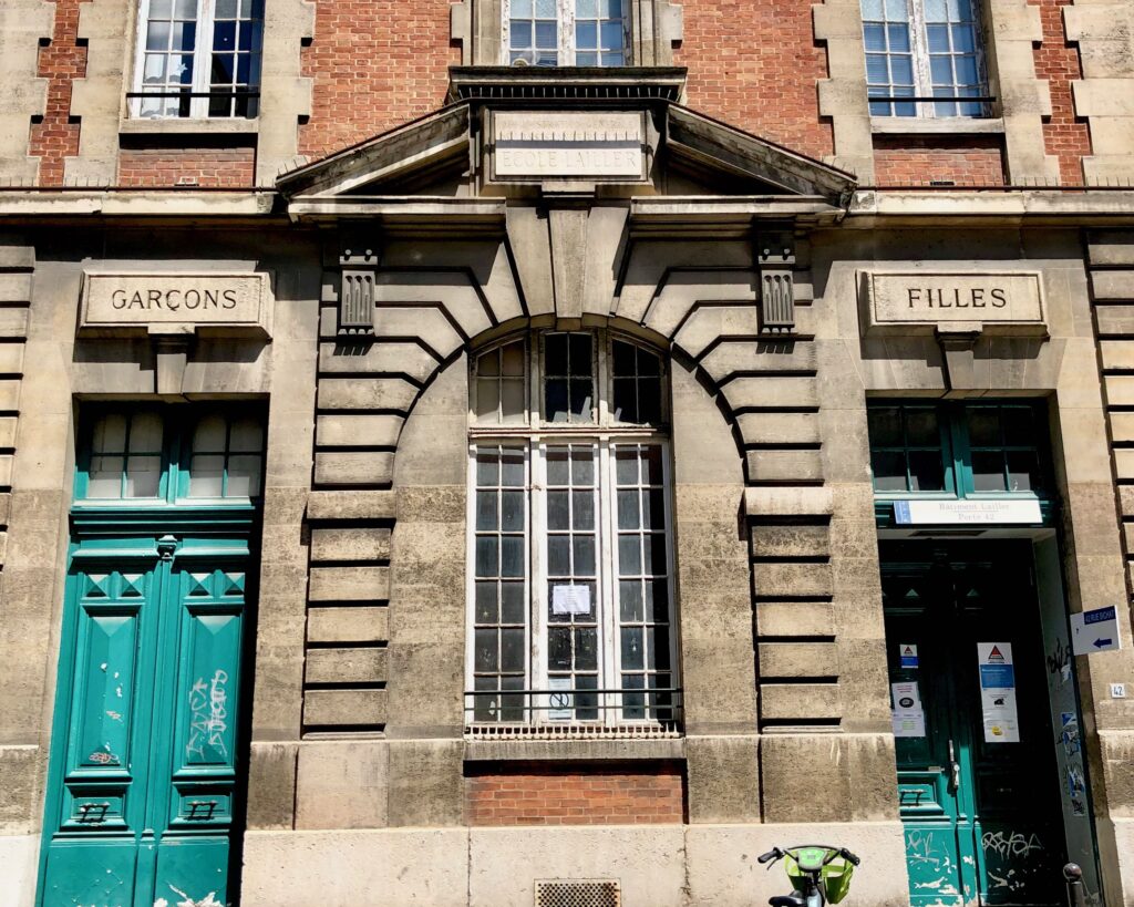 The facade of an elementary school in Paris with separate doors for boys (garçons) and girls (filles)
