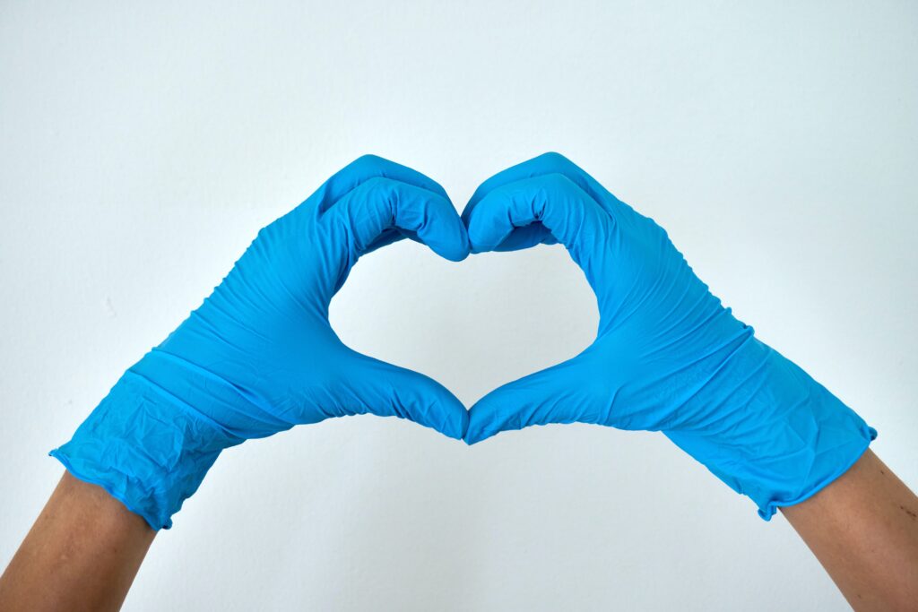Two hands with blue medical gloves forming a heart shape