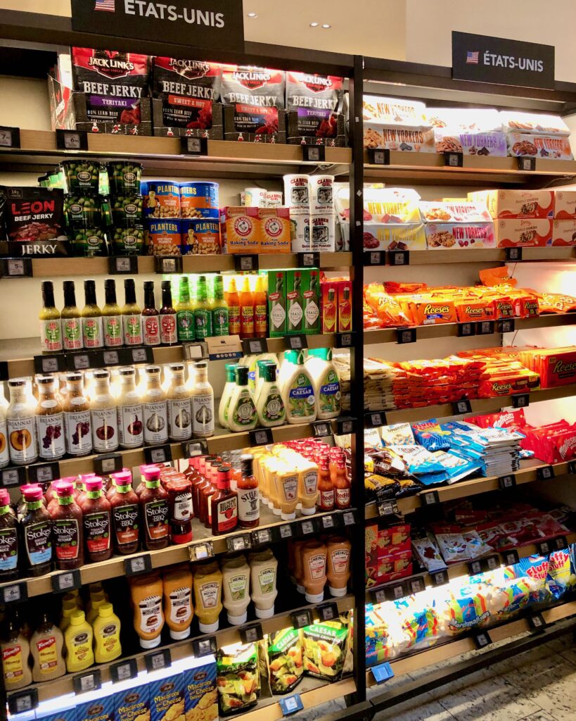 Shelves full of U.S. American products in a Parisian grocery store (La Grande Épicerie de Paris) including Reese's peanut butter cups, beef jerky, barbecue sauce, yellow mustard, baking powder, and marshmallows