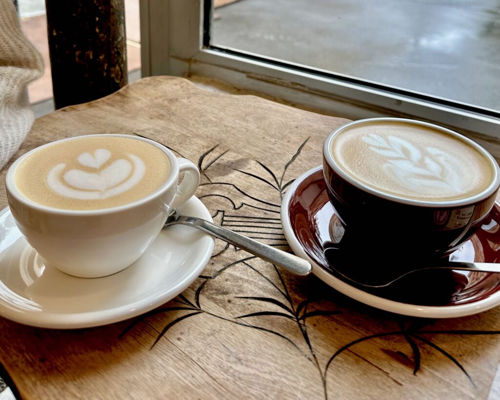 Two lattes in cups on saucers, side by side on a wooden table in a café in Paris