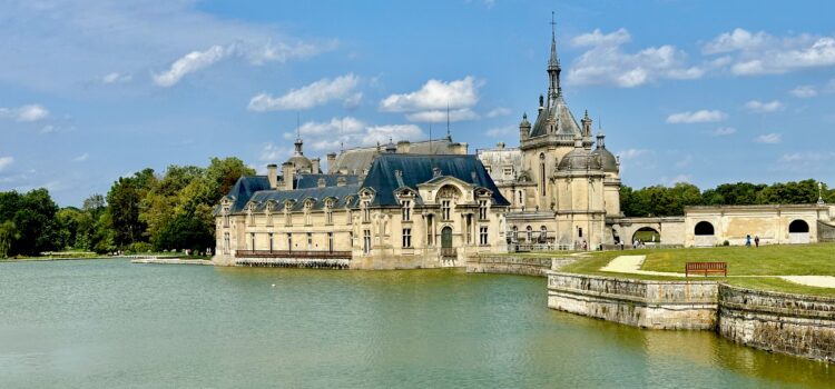 Discover Chantilly, France: Black Lace, Horses, and Whipped Cream Château de Chantilly from a distance with blue skies