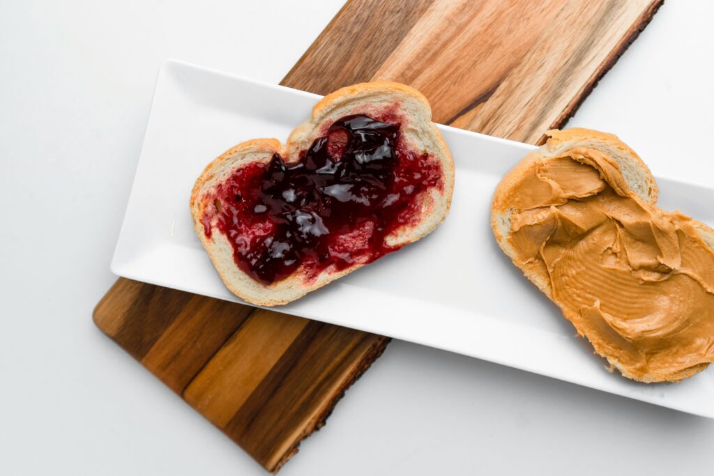 Two pieces of bread on a plate, one with jelly and one with peanut butter
